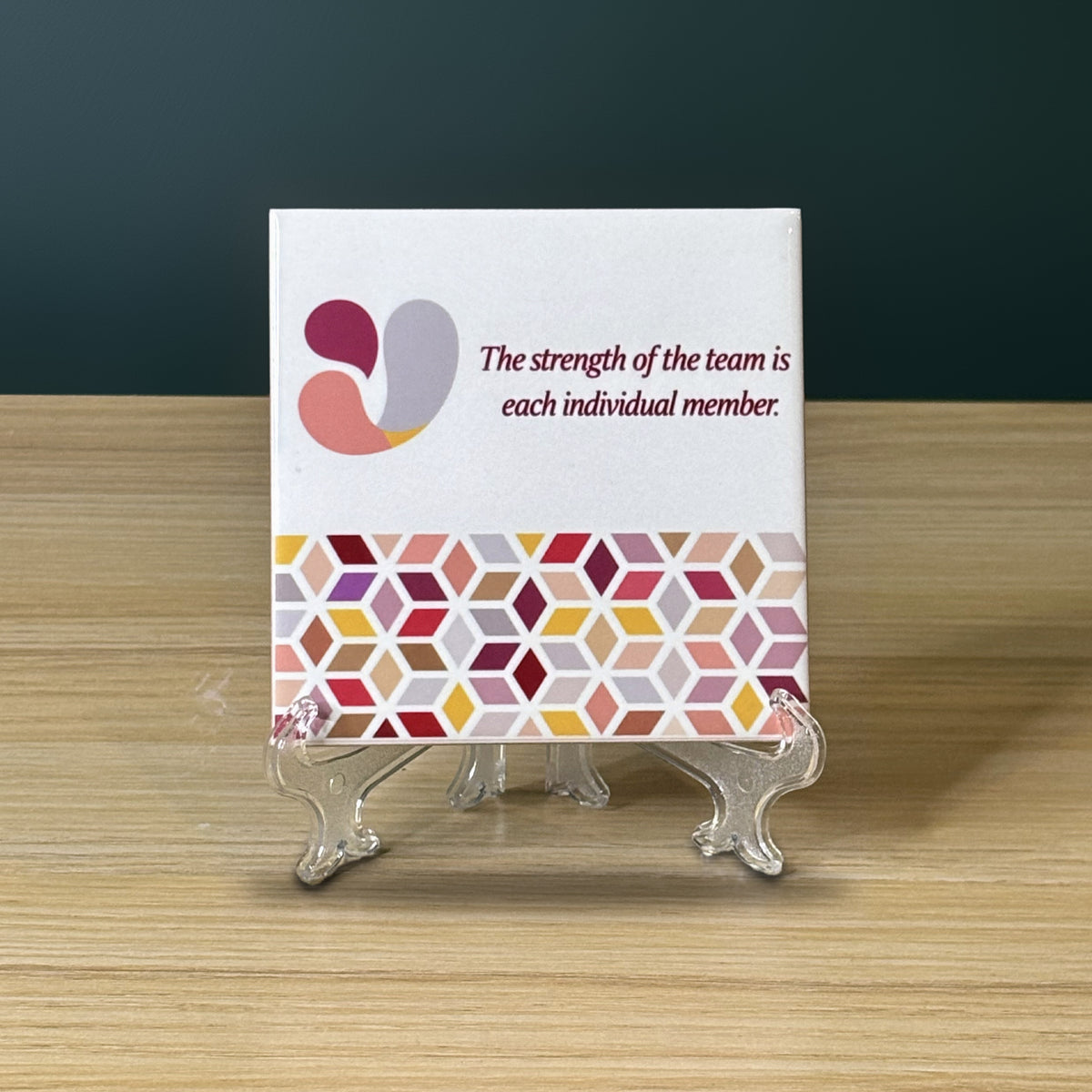 Azulejo blanc avec un logo d'entreprise, la citation The strength of the team is each individual member et une frise géométrique, sur un support transparent.